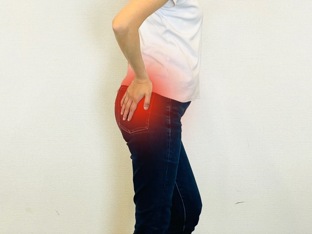 坐骨神経痛によりお尻から太ももにかけて痛む女性の様子。痛みの箇所が赤く示されている。