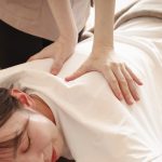 女性がうつ伏せで背中をマッサージされている画像。